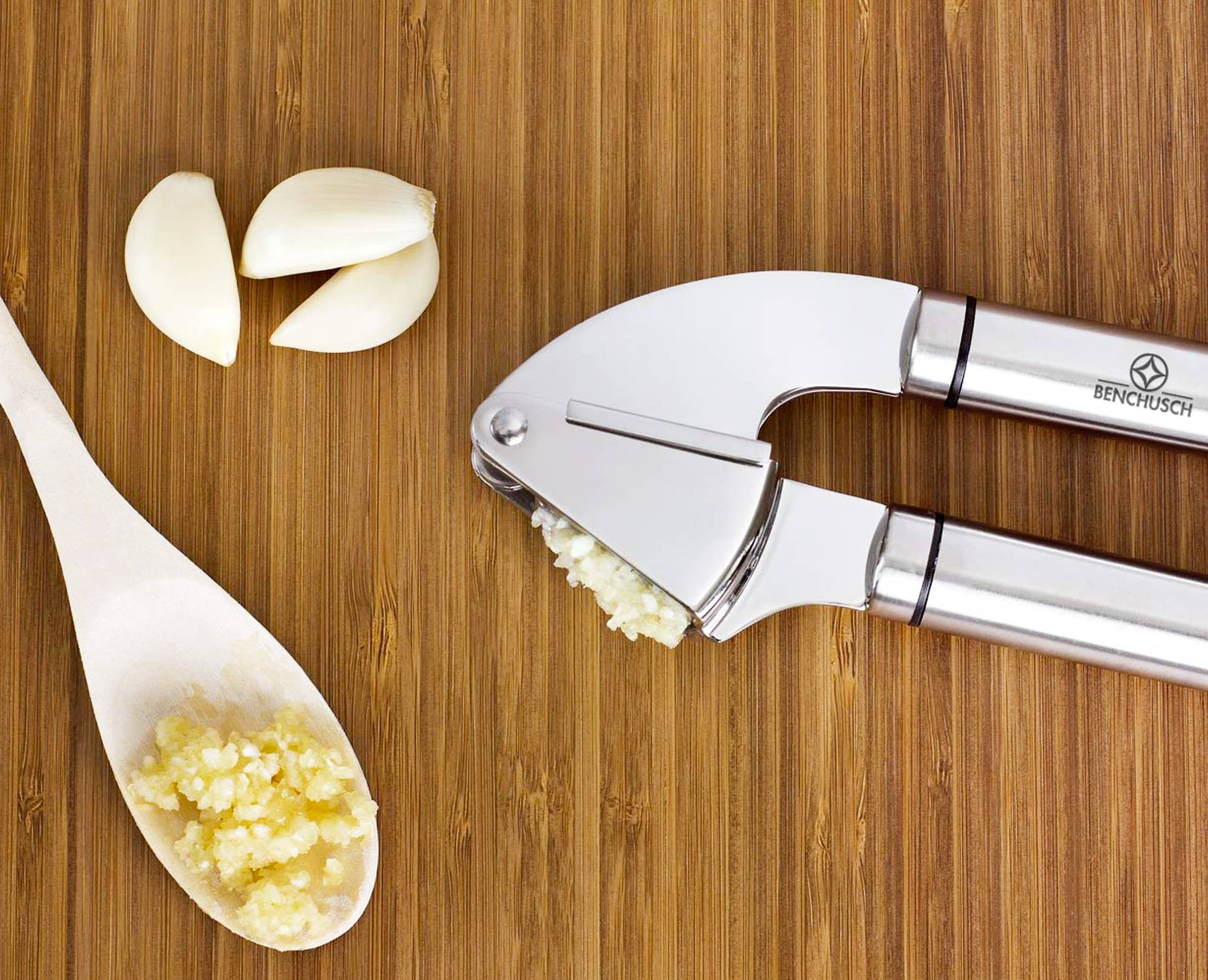 Benchusch garlic press with minced garlic and peeled garlic on the wooden background